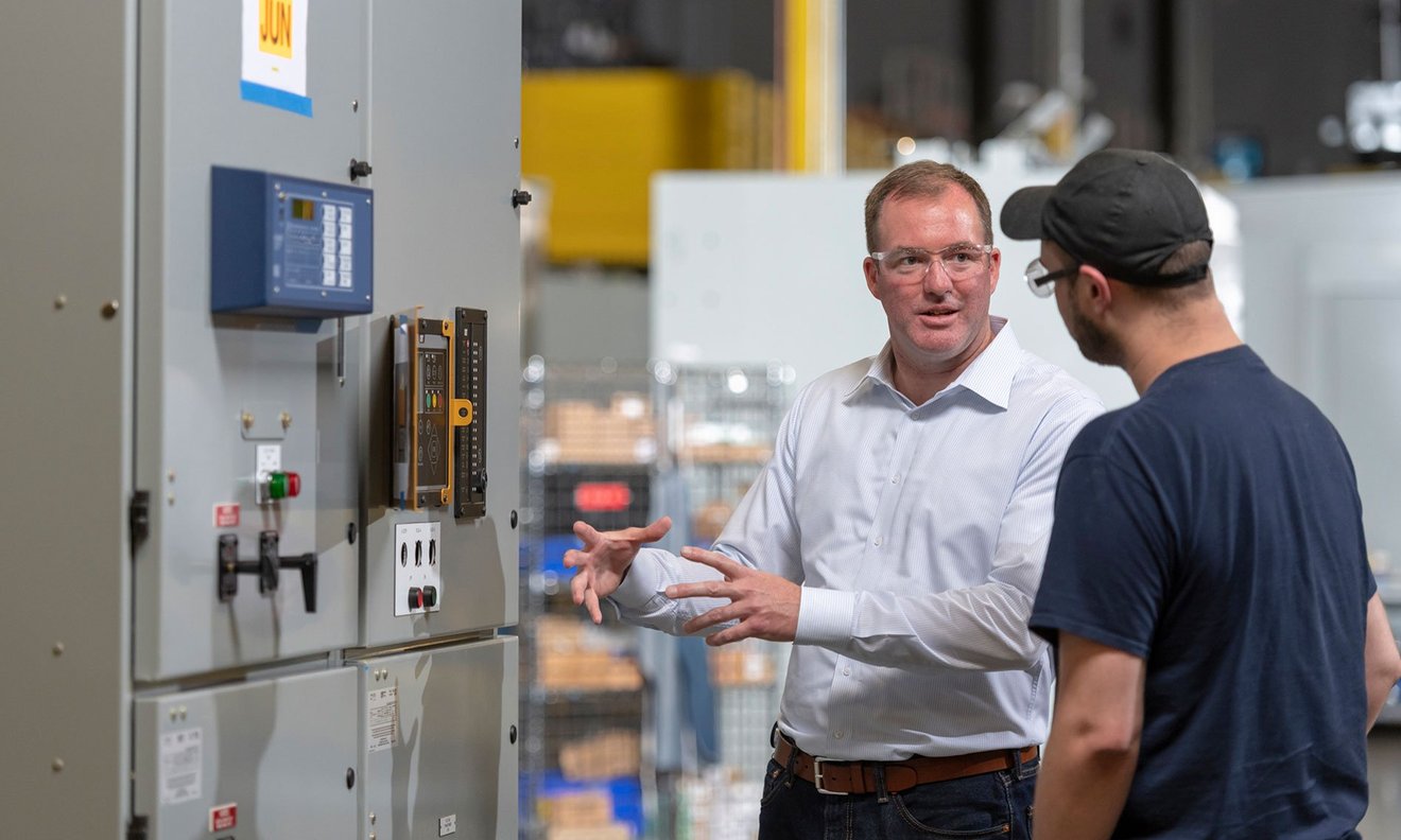 Two Men Talking In Front of Switchgear