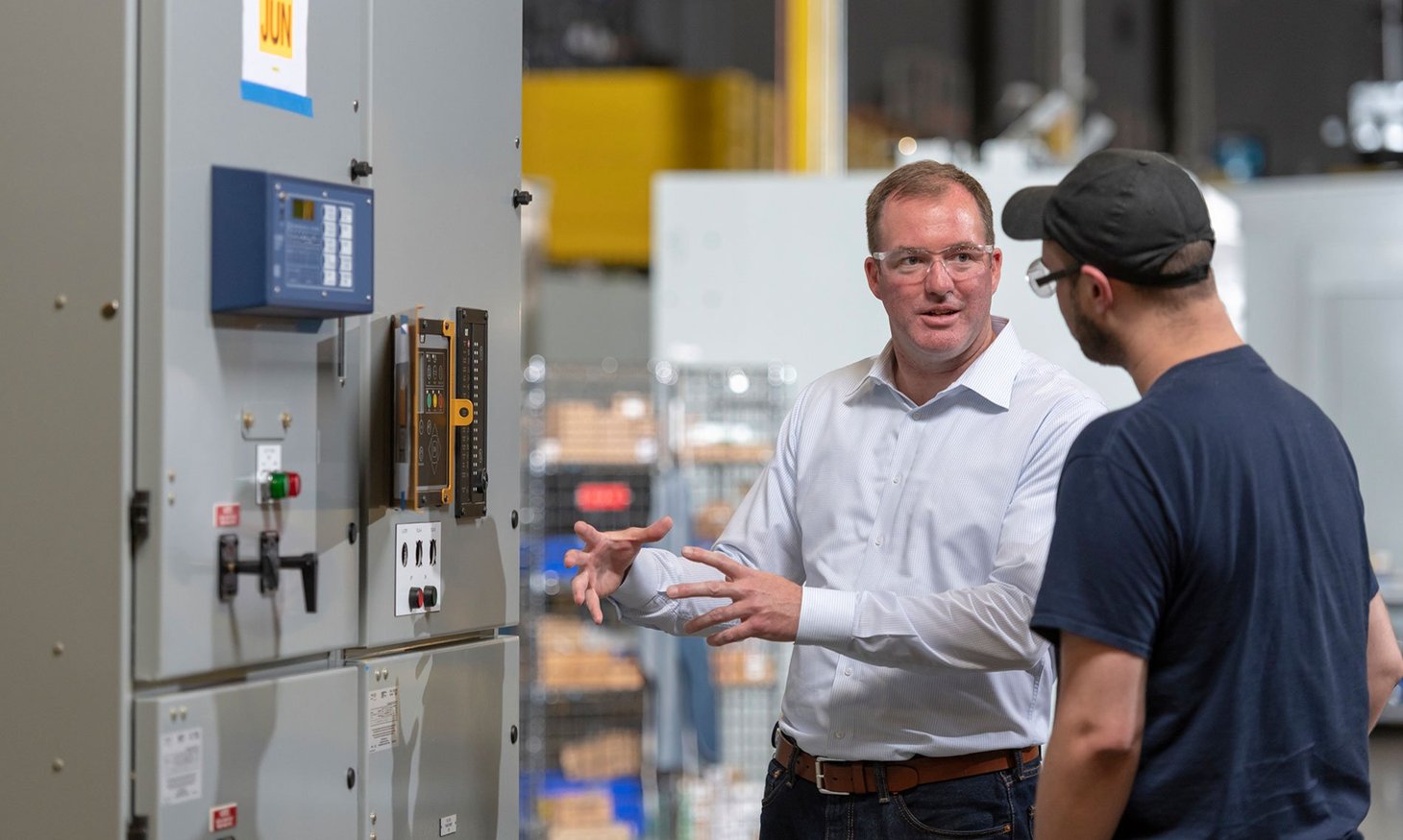 Two Men Talking In Front of Switchgear